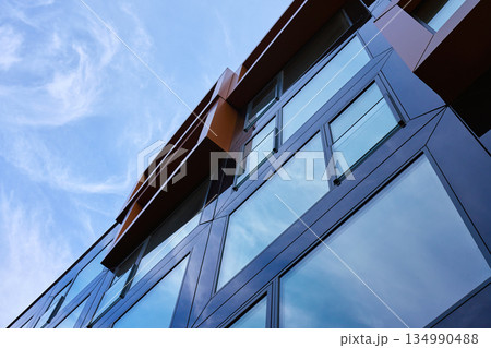 Modern building facade with large reflective glass windows and metal panels 134990488