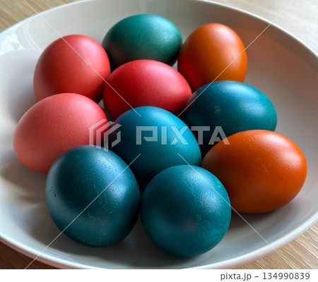 Colored Easter eggs arranged on plate in daylight. Holiday tradition, seasonal celebration, family ritual and decorative food styling 134990839
