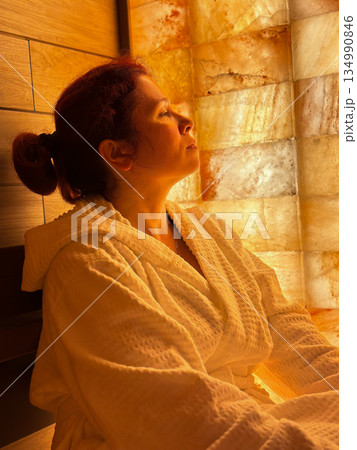 Side profile portrait of a woman resting in a salt spa room. Wellness relaxation, mindful breathing, healing atmosphere, self care, calm presence, and restorative moments focused on balance and health 134990846