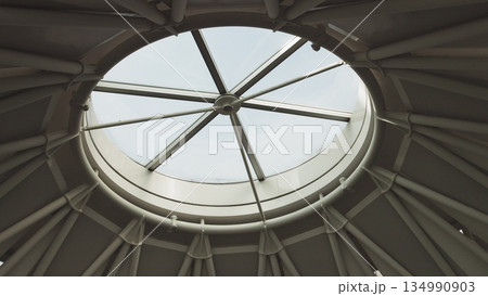 Top view on Structural glass facade curving roof of office building. Modern and contemporary architectural fiction with glass steel column. Aerial shot of glass dome construction. 134990903