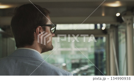 A young businessman, an employee of a large company walks around a modern beautiful office and greets, waves his hand. Shooting with hands close up. The concept of a successful employee A young businessman, an employee of a large company walks around a modern beautiful office and greets, waves his hand. Shooting with hands close up. The concept of a successful employee 134990938
