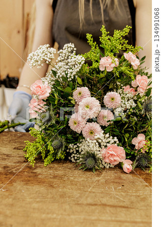 Florist arranging bouquet of pink and white flowers on wooden table, Mothers day Florist arranging bouquet of pink and white flowers on wooden table, Mothers day 134991068