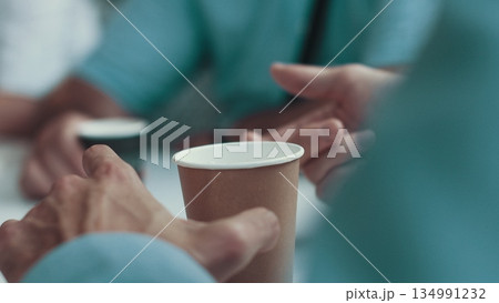 close up of coffee on the table and businessman's hands. A man drinking coffee at a meeting with customers. Pleasant meeting of employees over a cup of coffee close up of coffee on the table and businessman's hands. A man drinking coffee at a meeting with customers. Pleasant meeting of employees over a cup of coffee 134991232