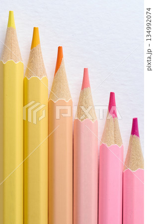 Close-up of six sharp-tipped colored pencils arranged horizontally with color gradation from hot pink to light yellow 134992074