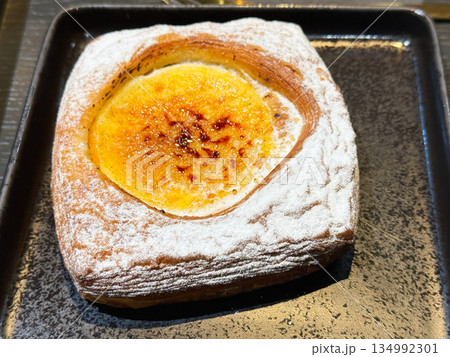 Cream puff pastry sprinkled with powdered sugar on black plate. Cream puff pastry sprinkled with powdered sugar on black plate. 134992301