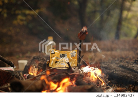焚き火と共に加熱するレトルトカレーと串焼き肉 134992437