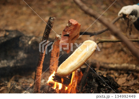 焚き火で焼くパンと肉のキャンプ料理 134992449