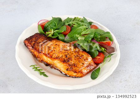 Grilled salmon fillet with fresh green salad, vegetables on white background. Healthy lunch concept. Grilled salmon fillet with fresh green salad, vegetables on white background. Healthy lunch concept. 134992523
