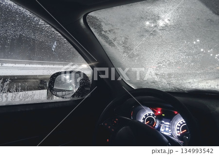 Safety driving. Car with frozen windshield stopped on roadside in the night snowfall 134993542