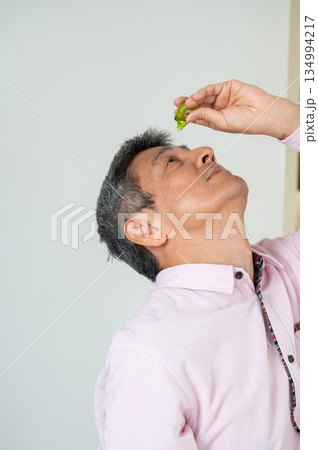 椅子に座って目薬をさす男性 椅子に座って目薬をさす男性 134994217