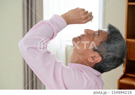 椅子に座って目薬をさす男性 椅子に座って目薬をさす男性 134994219