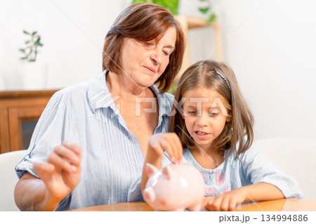 Grandmother and granddaughter saving money Grandmother and granddaughter saving money 134994886
