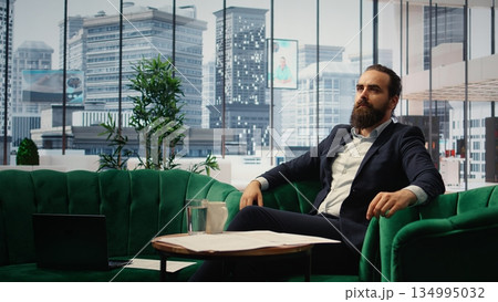 Male entrepreneur studying investments on a hologram illustration, using holography technology for productivity in smart office corporation. Boss looks at holographic image. Camera A. 134995032