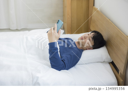 ベッドでスマホを見る若い男性 134995356