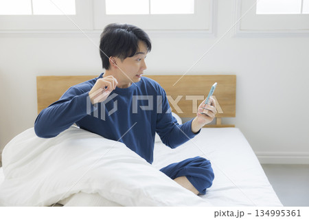 ベッドでスマホを見る若い男性 134995361