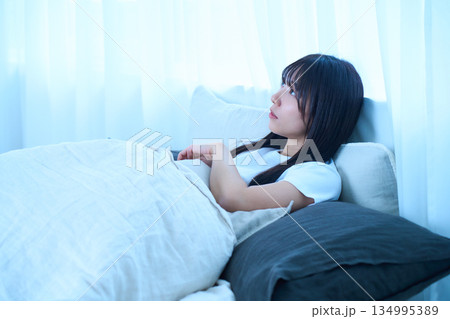 朝の光を浴びてベッドでまどろむ若い日本人女性 ライフスタイル・健康イメージ 134995389