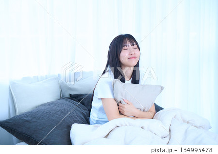 ベッドでクッションを抱いている若い女性 134995478
