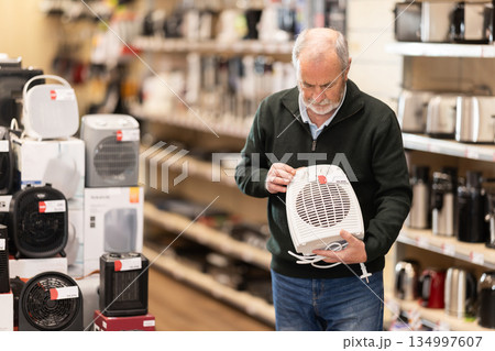Elderly man choosing a portable heater Elderly man choosing a portable heater 134997607