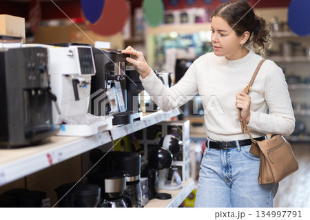 Young woman choosing a coffee machine in a hardware store Young woman choosing a coffee machine in a hardware store 134997791