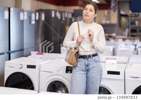 woman chooses a dishwasher and a washing machine in appliance store woman chooses a dishwasher and a washing machine in appliance store 134997833