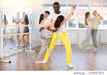 Middle-aged man and woman practicing salsa dance in pair in training hall 134997855