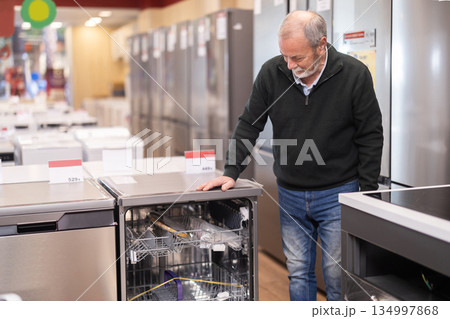 Eldery man chooses dishwasher in appliance store 134997868