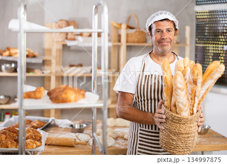 Adult male baker with basket of baguettes Adult male baker with basket of baguettes 134997875