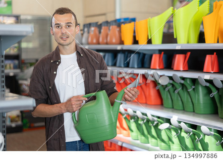 Man buys a garden watering can at hardware store Man buys a garden watering can at hardware store 134997886