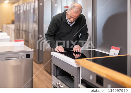 elderly man chooses a stove in a hardware store 134997959