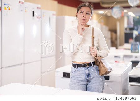 woman chooses a dishwasher and a washing machine in appliance store woman chooses a dishwasher and a washing machine in appliance store 134997963