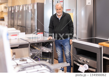 Senior man customer inspect product range and selects kitchen oven Senior man customer inspect product range and selects kitchen oven 134998062