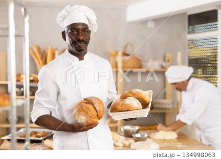 Successful African American baker holding freshly baked bread 134998063