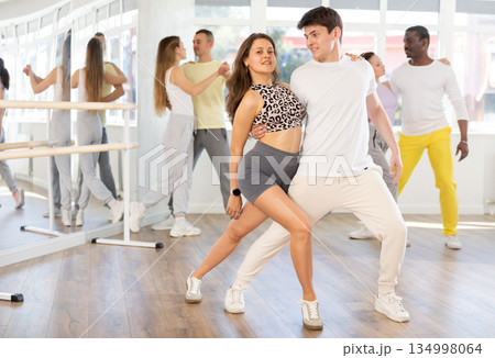 Pairs practicing Latino dance in training hall during dancing-classes. Pairs training ballroom dance Pairs practicing Latino dance in training hall during dancing-classes. Pairs training ballroom dance 134998064