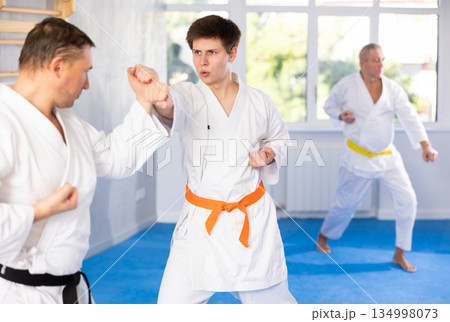 Young karate fighter working on punches in sparring with master at training Young karate fighter working on punches in sparring with master at training 134998073