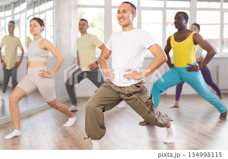Young Asian man doing leg exercises in training hall 134998115