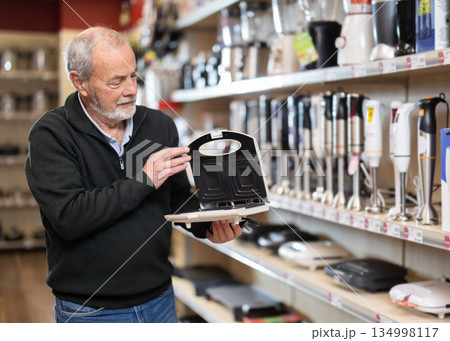 Elderly man chooses pancake maker at appliance store Elderly man chooses pancake maker at appliance store 134998117