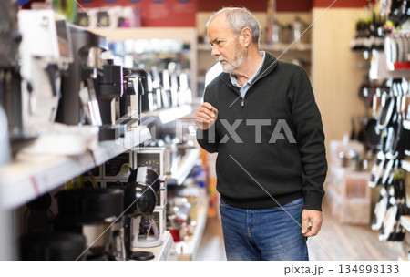 Elderly man choosing a coffee machine for his kitchen 134998133