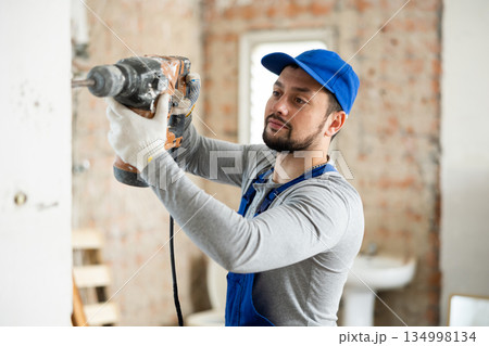 Confident builder posing on indoor construction site 134998134