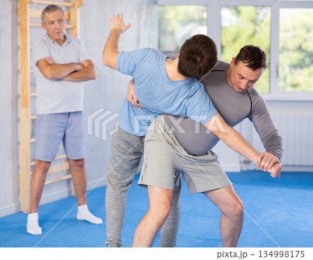 Man practicing throws in sparring with guy during self-defence workout Man practicing throws in sparring with guy during self-defence workout 134998175