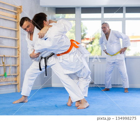 Experienced karate instructor demonstrating techniques in sparring with young fighter 134998275