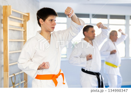 Fighting stance of men of different ages during group karate training. Guy trains punches 134998347