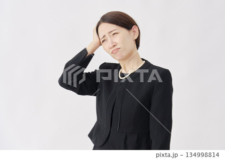 頭を抱える喪服を着た女性　白背景 134998814