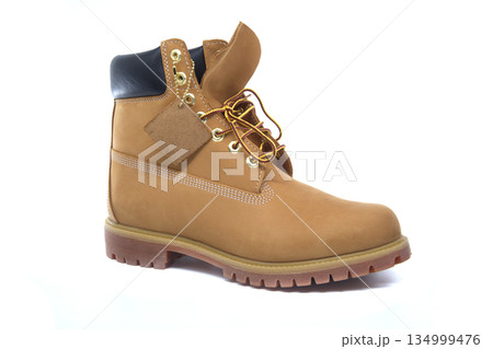 Iconic tan work boot with yellow laces and a leather tag, isolated on a white background Iconic tan work boot with yellow laces and a leather tag, isolated on a white background 134999476