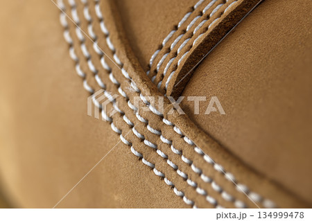 Close-up of tan suede material with detailed white stitching and texture Close-up of tan suede material with detailed white stitching and texture 134999478