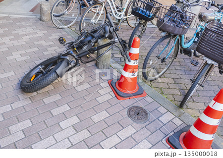 歩道上で転倒して駐輪している大型自転車と設置されたカラーコーン 135000018