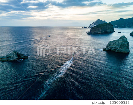 夕暮れのヒリゾ浜沖のドローン撮影。サンセットクルージングの漁船が航行している。ヒリゾ浜南伊豆町中木 135000532