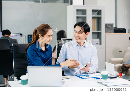 Asian business team collaborating in a modern office, showcasing teamwork, success, and innovation in corporate workplace settings. 135000931