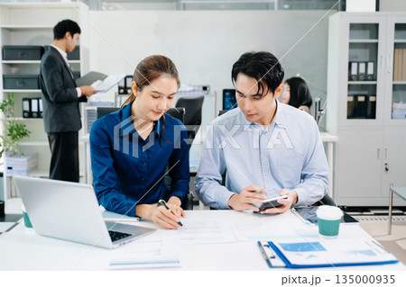 Young Asian professionals collaborating in modern office, discussing business strategy, teamwork, and success. Perfect for corporate, startup Young Asian professionals collaborating in modern office, discussing business strategy, teamwork, and success. Perfect for corporate, startup 135000935