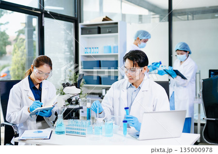 cientists working together in a modern lab with microscopes and blue liquids, symbolizing chemistry, biotechnology, and scientific innovation. cientists working together in a modern lab with microscopes and blue liquids, symbolizing chemistry, biotechnology, and scientific innovation. 135000978