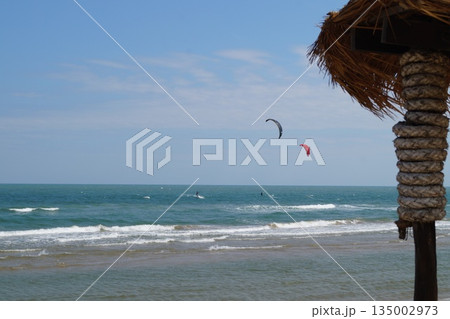 A cozy place to relax on the beach.A beautiful place to relax and unwind on the beach by the sea. A beautiful bamboo and straw bar counter sits against a backdrop of blue sky and turquoise sea. 135002973